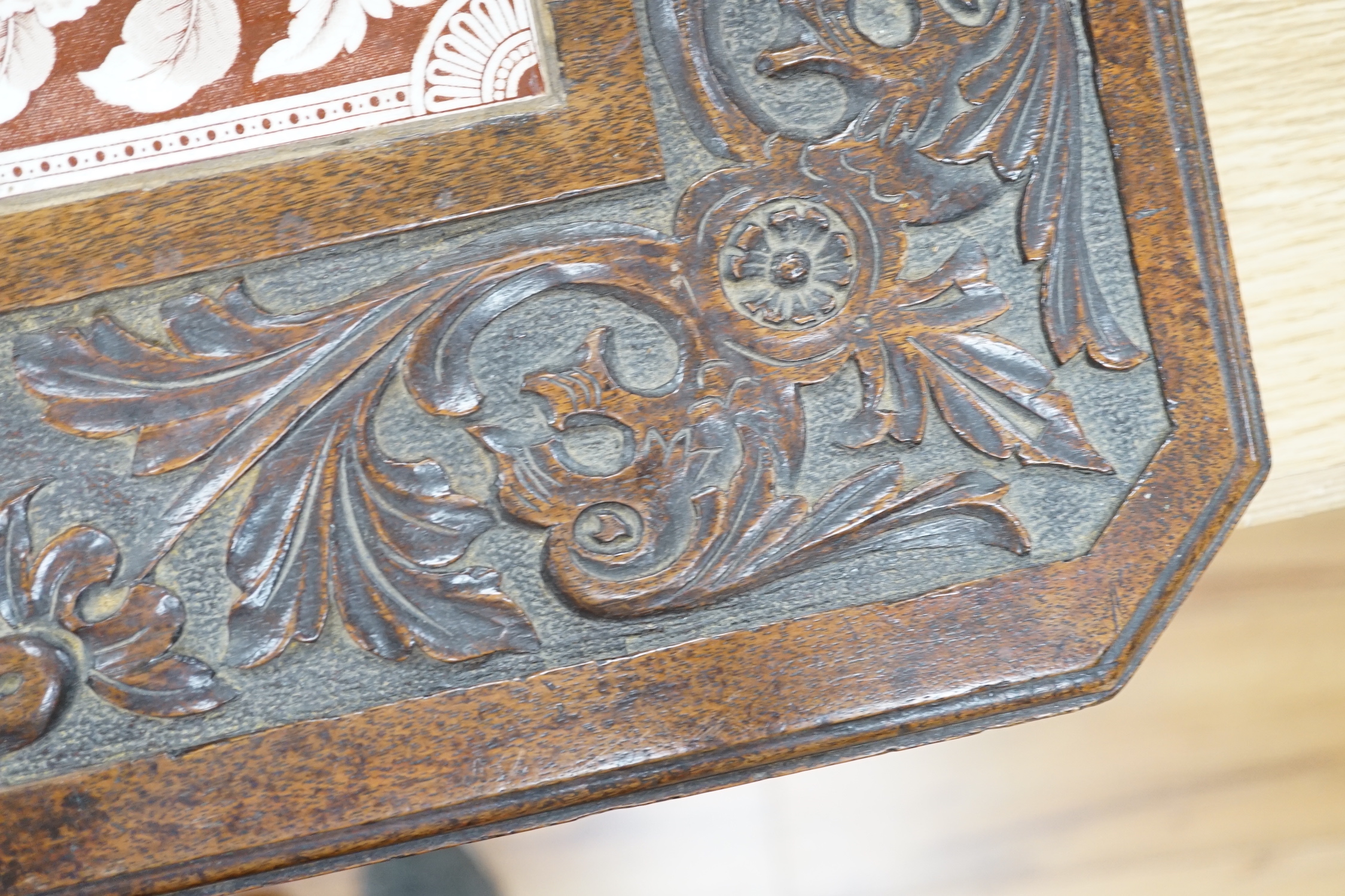 A Victorian carved oak stand inset with there floral tiles, 69cm wide